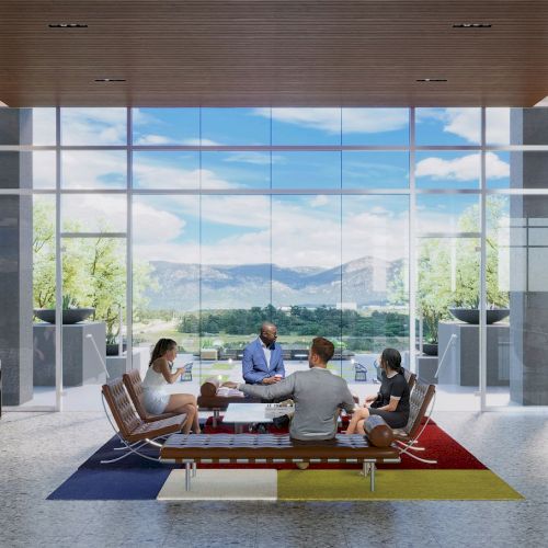 A group of people sit and converse in a modern, open space with large windows offering a scenic view of mountains and greenery.