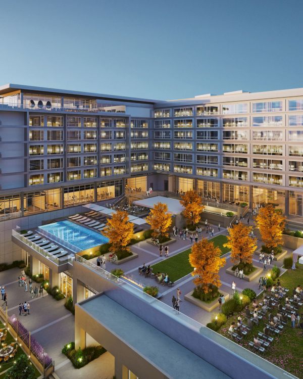 A modern building complex with a rooftop pool, courtyard, trees, tables, and people gathering, possibly for an event or gathering.