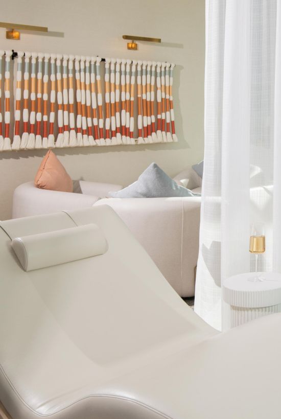 A tranquil lounge space with white lounge chairs, soft pillows, and sheer curtains, offering a relaxing atmosphere.