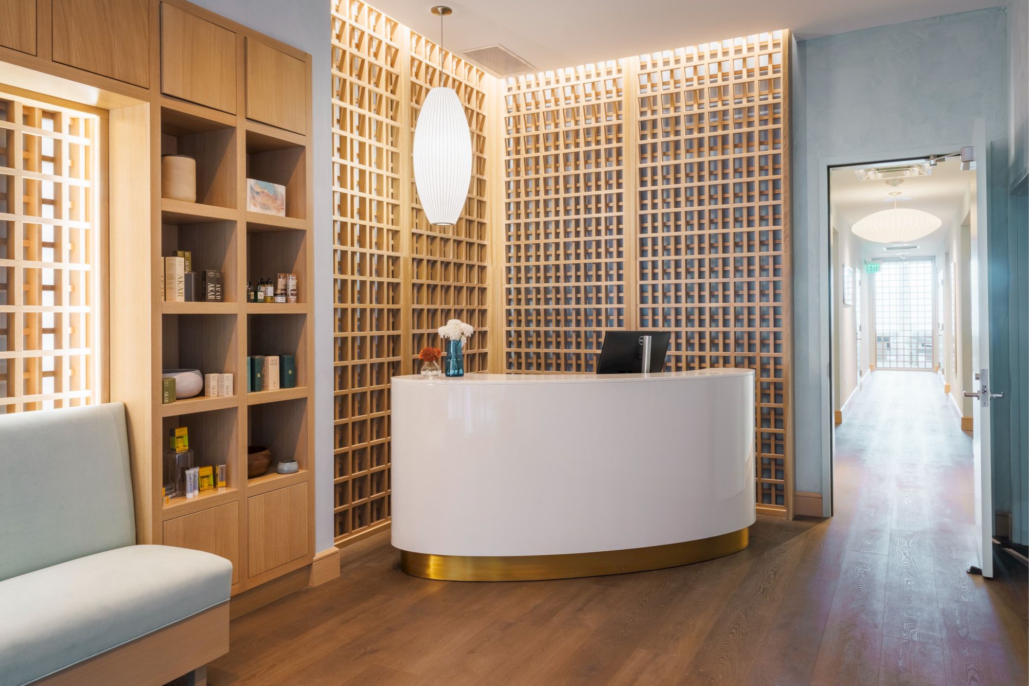 A modern reception area with a curved white desk, shelves with products, and warm lighting, creating a welcoming atmosphere.