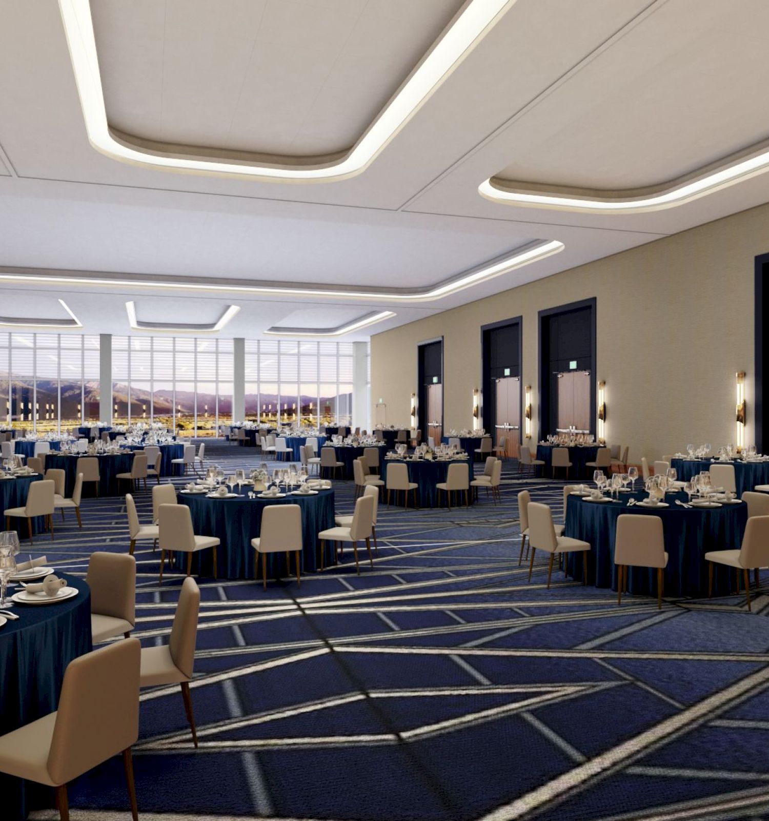 An elegantly decorated banquet hall with round tables set for dining, blue tablecloths, white chairs, and large windows allowing natural light.