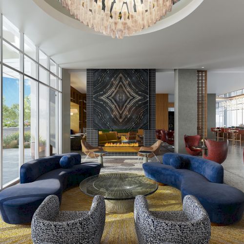 Modern lobby with curved seating, sleek decor, large windows, abstract art, and chandelier, creating a luxurious and inviting atmosphere.