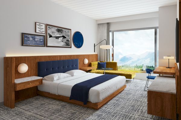 A modern hotel room with a king-sized bed, wall art, a yellow sofa, a large window with a mountain view, and wooden furniture finishes the view.