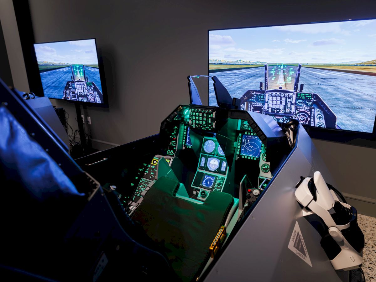 The image shows a flight simulator with a cockpit setup and screens displaying a runway, providing a realistic training experience.