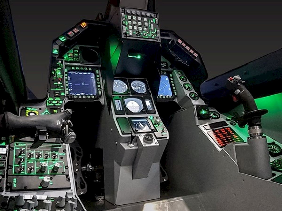 This image depicts a modern aircraft cockpit featuring numerous controls, displays, and instruments illuminated with green lighting.