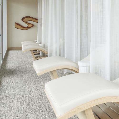 The image shows a relaxing spa area with white lounge chairs and curtains, set against light-colored walls with a subtle abstract wall decoration.