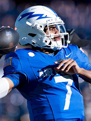 A football player in a blue jersey and helmet is preparing to throw a ball during a game.