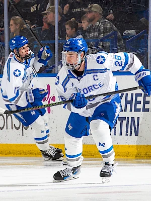 Hockey players in blue and white uniforms on ice, one with 