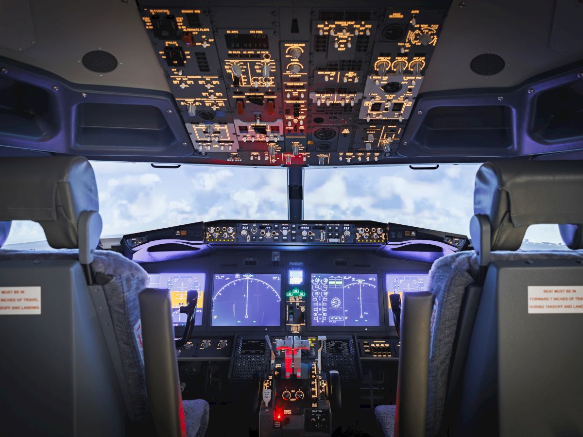 This image shows the interior of an airplane cockpit with various controls, seats, and displays, capturing the flight deck's detailed setup.
